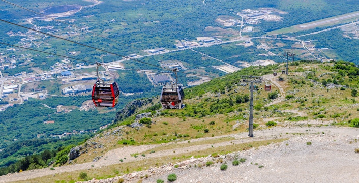 Cable car ascending over the Bay of Kotor, Montenegro, with scenic landscape views.