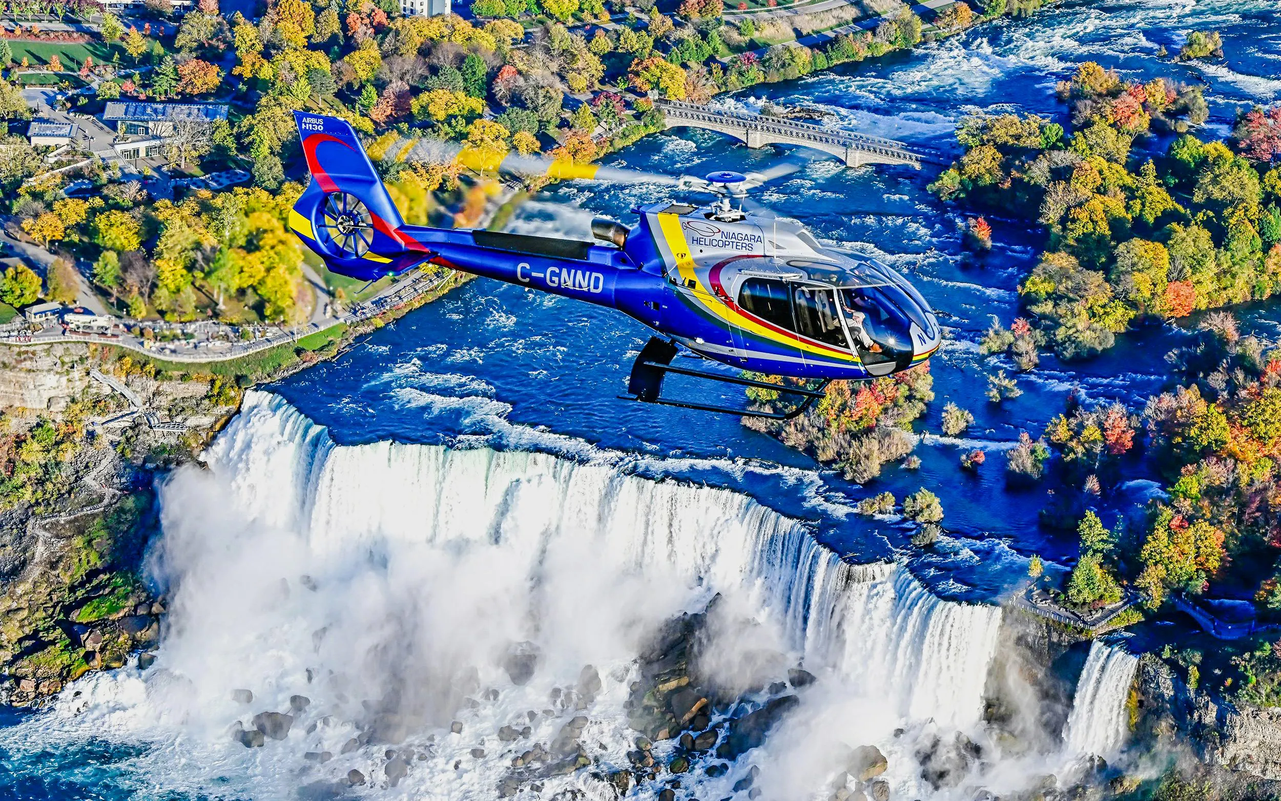 Helicopter flying over Niagara Falls in Canada during autumn.