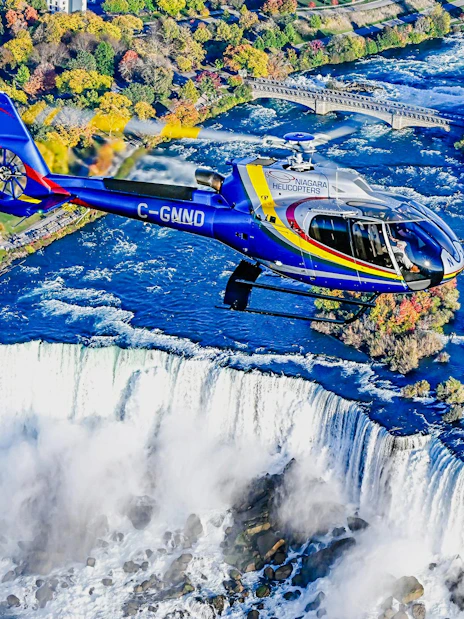 Helicopter flying over Niagara Falls in Canada during autumn.