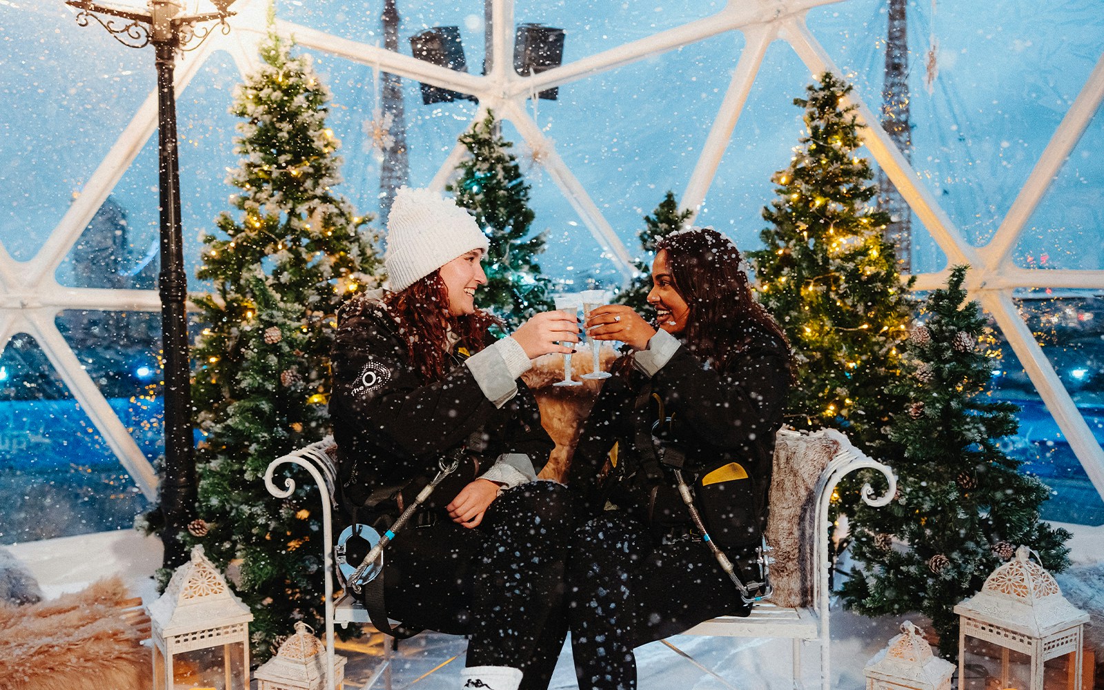 Two people toasting inside a snow-covered dome at the Up At The O2 Christmas experience.