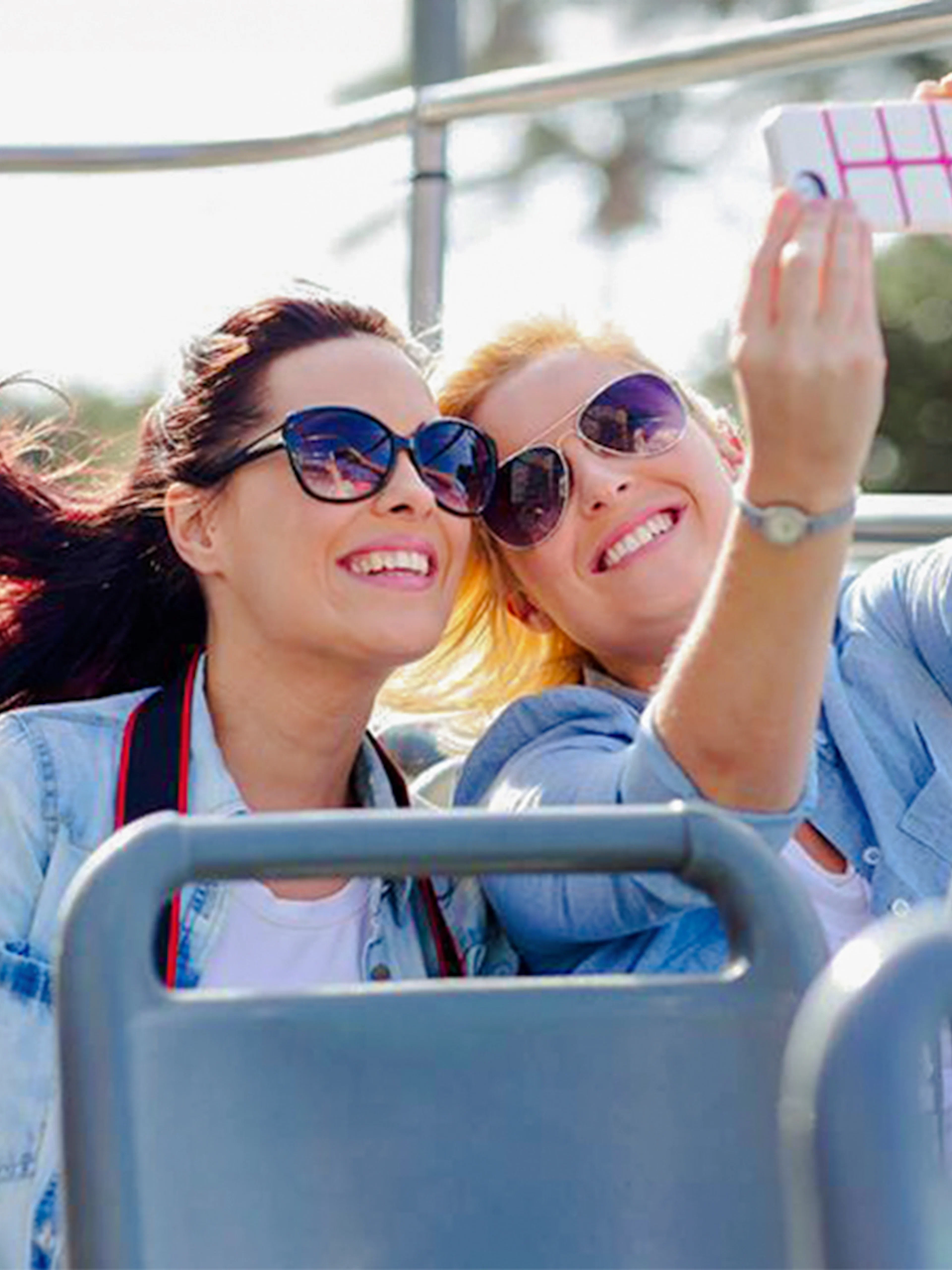 Two women taking a selfie on an open-top bus tour.