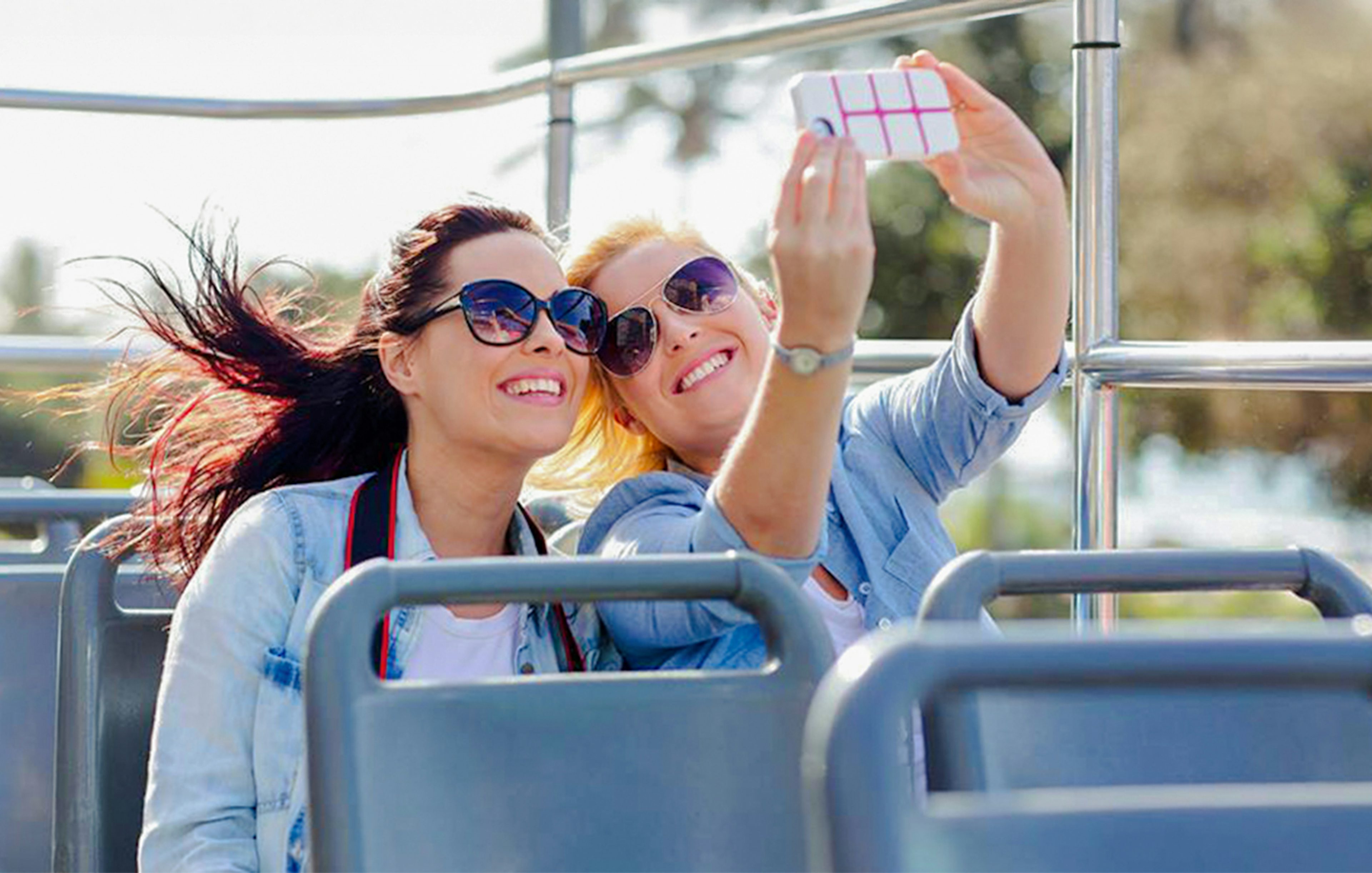 Two women taking a selfie on an open-top bus tour.