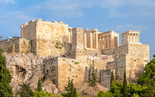 Acropolis in Athens with tourists on a guided tour, showcasing ancient ruins and architecture.