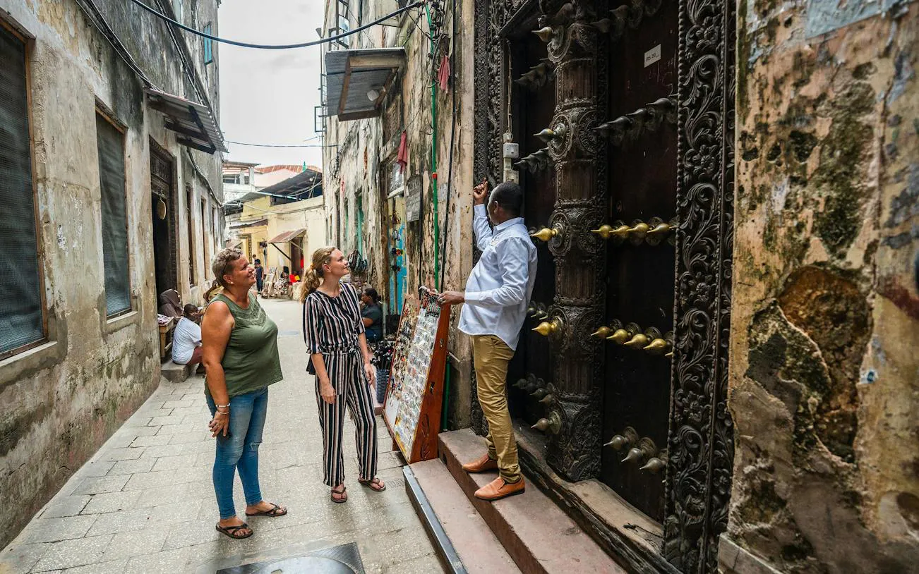 Tour guide explaining ornate door to visitors in Stone Town, Zanzibar.