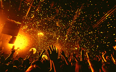 Nightclub crowd dancing under confetti and lights.