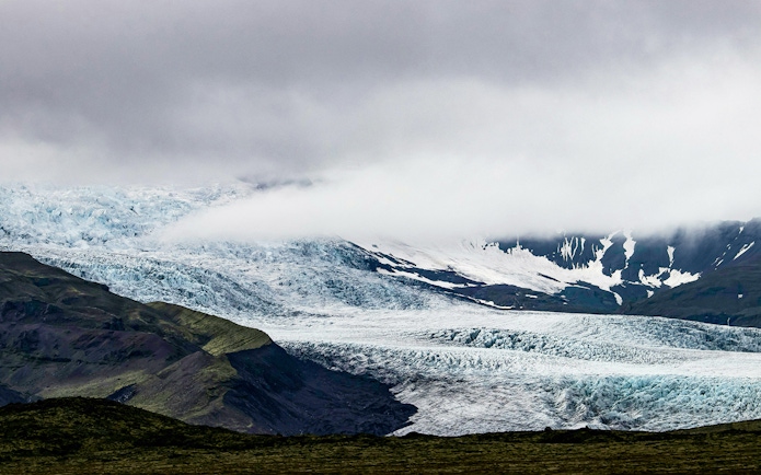 Solheimajökull Glacier with ice formations and surrounding mountains in Iceland.