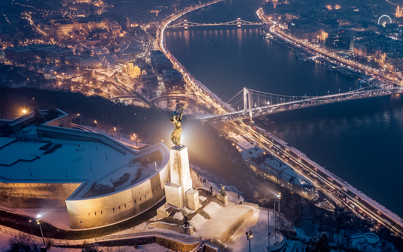 Liberty Statue in Budapest illuminated at dusk with cityscape in the background.
