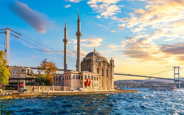 Ortaköy Mosque and Bosphorus Bridge at sunset during a yacht cruise in Istanbul.