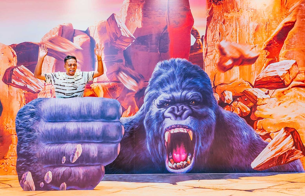 Man posing with 3D gorilla art at Trick Eye Museum, Singapore.