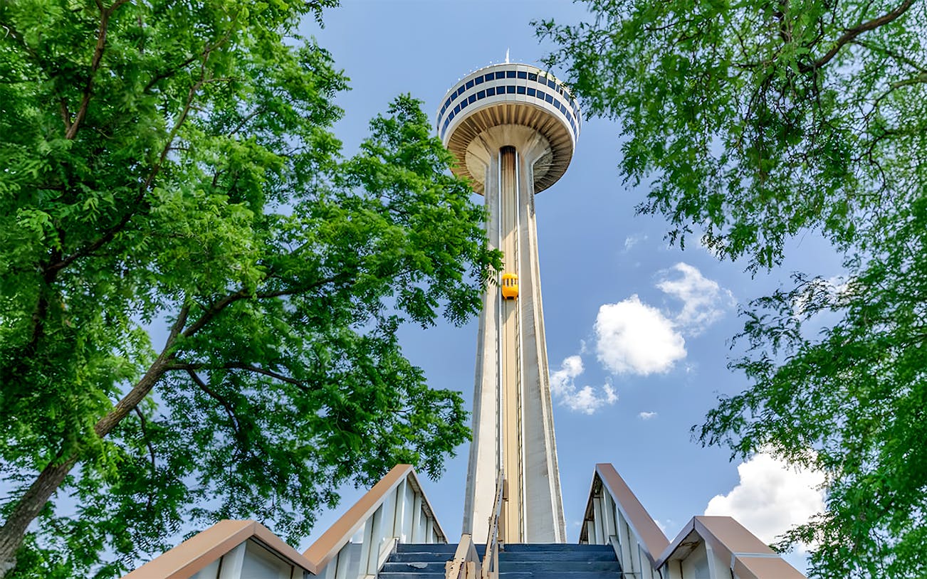 Skylon Tower viewed from below with surrounding trees and blue sky.