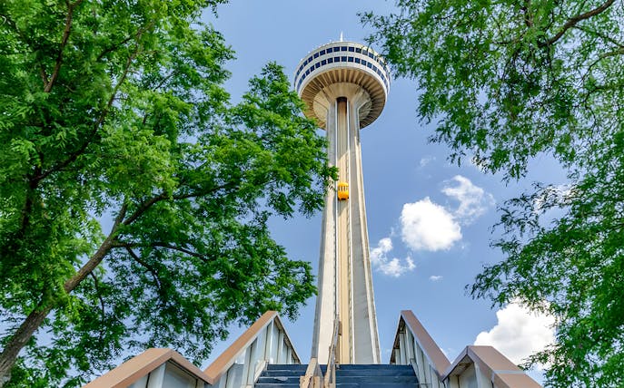 Skylon Tower viewed from below with surrounding trees and blue sky.