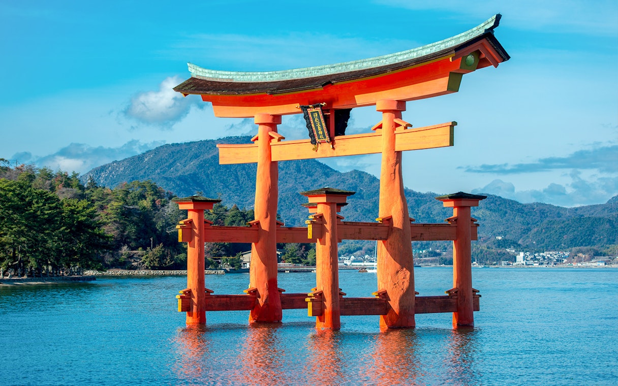 Torii gate at Itsukushima Shrine, Miyajima, with mountains in the background.