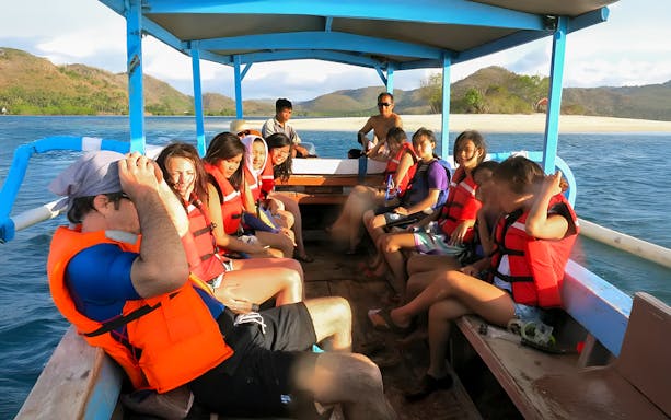 Group on a boat wearing life vests, heading to snorkeling trip, Northern Coast Gili Islands.