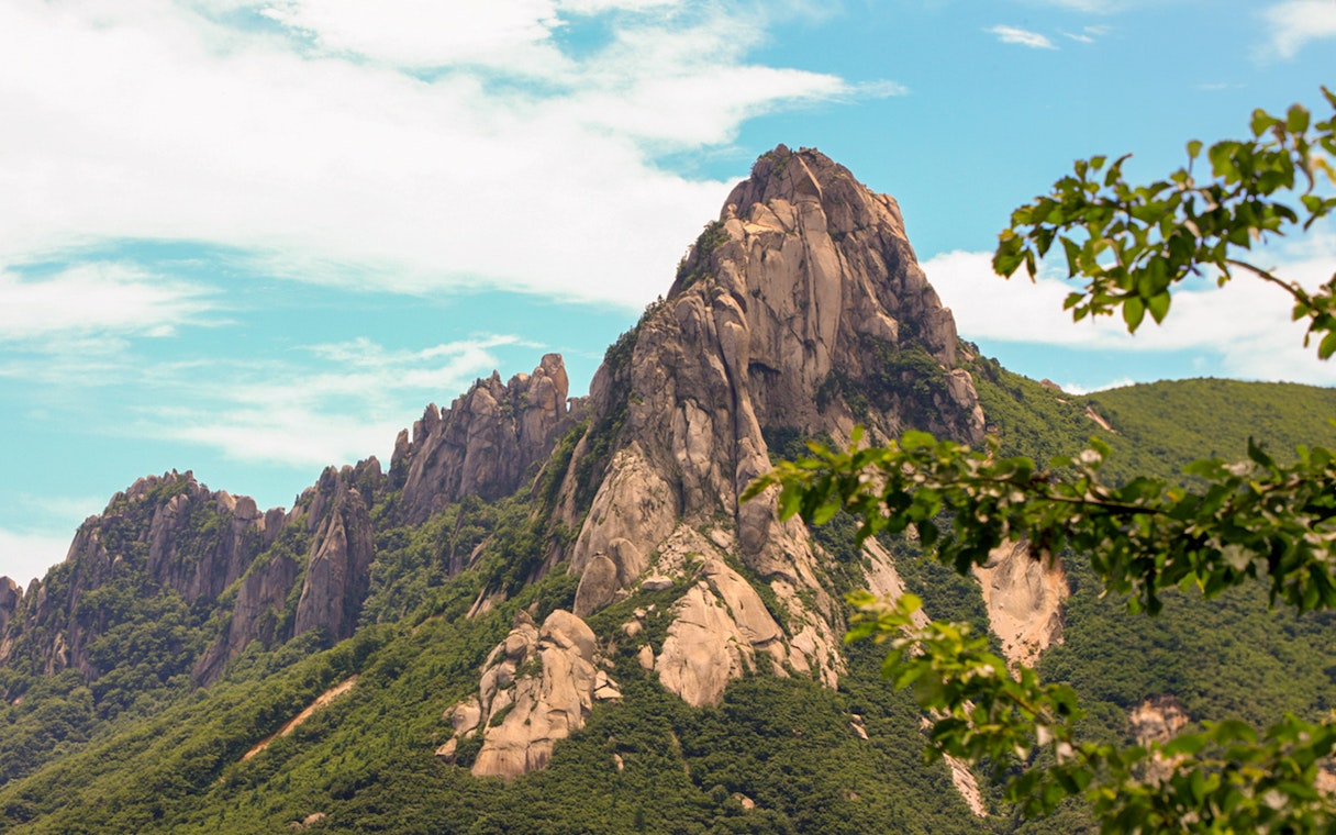 Mt. Seorak rocky peak with lush greenery under a blue sky, South Korea.