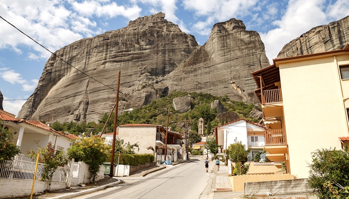 Street view of Meteora rock formations in Kalambaka, Greece, with residential buildings.