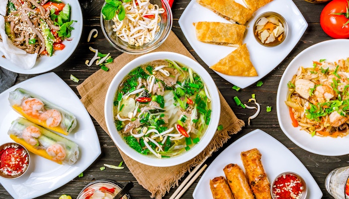 Vietnamese dishes including pho, spring rolls, and noodle salad arranged on a table.