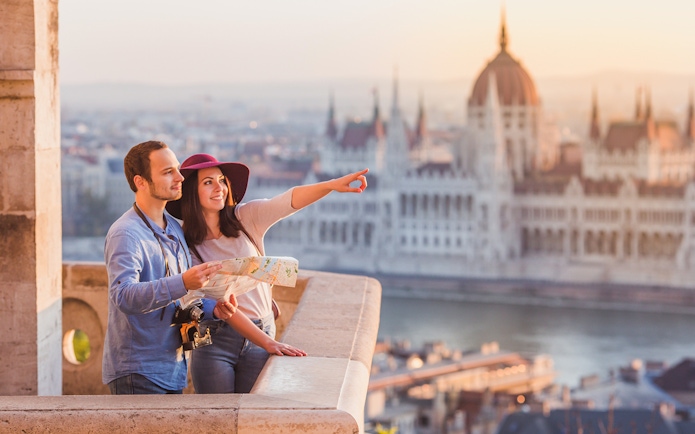 Couple with map enjoying view of Budapest Parliament building.
