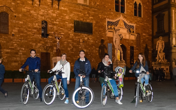 Group on e-bikes in front of Palazzo Vecchio during Florence night tour.