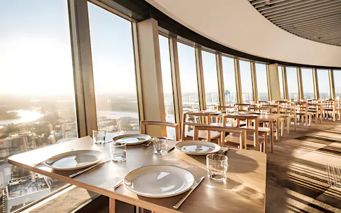 Dining tables set at SkyFeast, Sydney Tower, with panoramic city views.