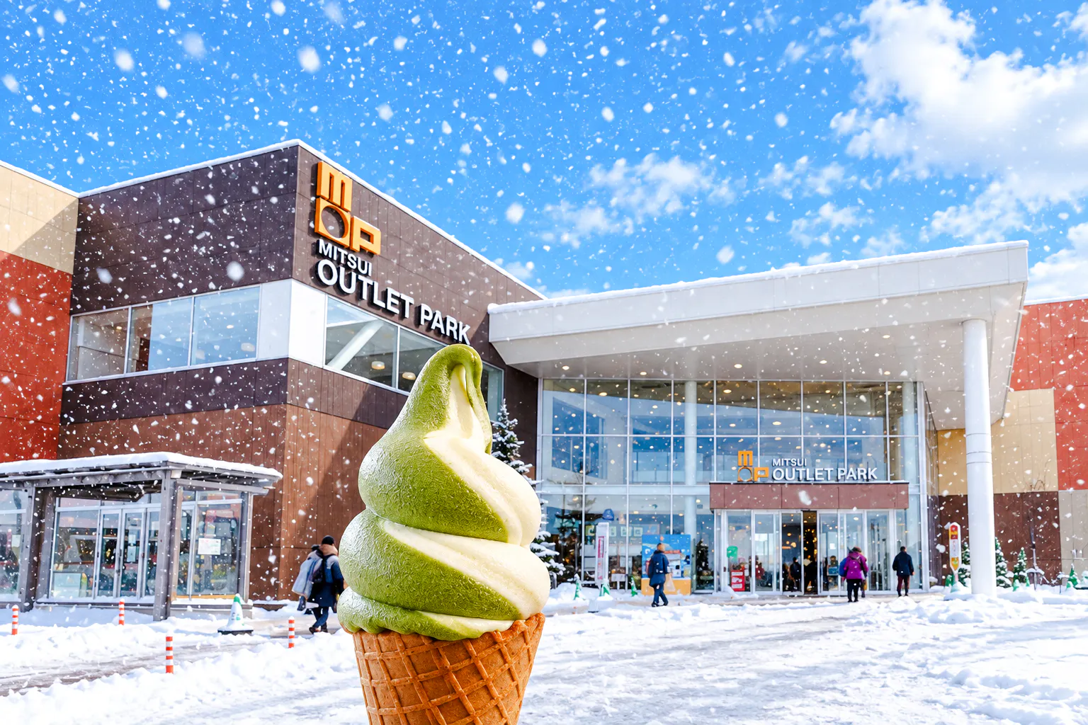 Mitsui Outlet Park in Sapporo with matcha ice cream cone in foreground during snowfall.