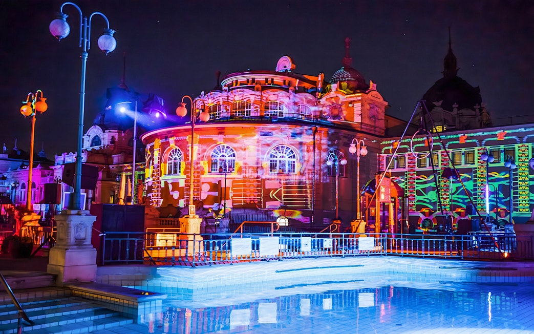 Colorful lights illuminate the Széchenyi Thermal Bath during a Sparty in Budapest.