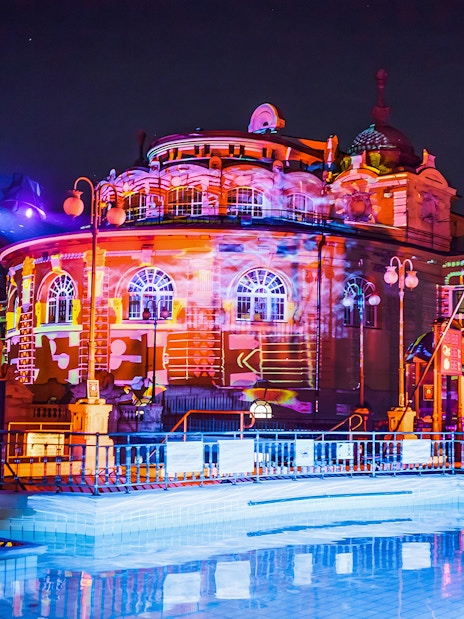 Colorful lights illuminate the Széchenyi Thermal Bath during a Sparty in Budapest.