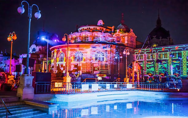 Colorful lights illuminate the Széchenyi Thermal Bath during a Sparty in Budapest.
