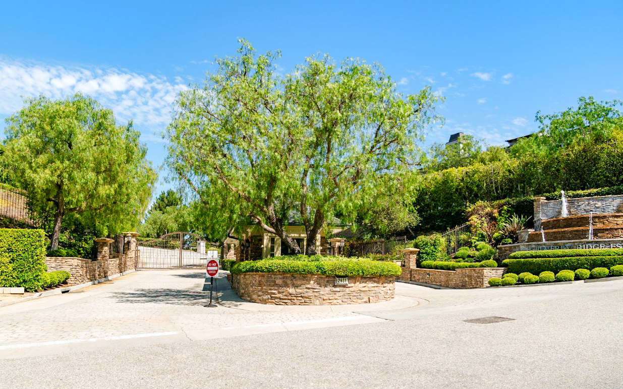 Gated entrance to a celebrity home in Los Angeles surrounded by lush greenery.