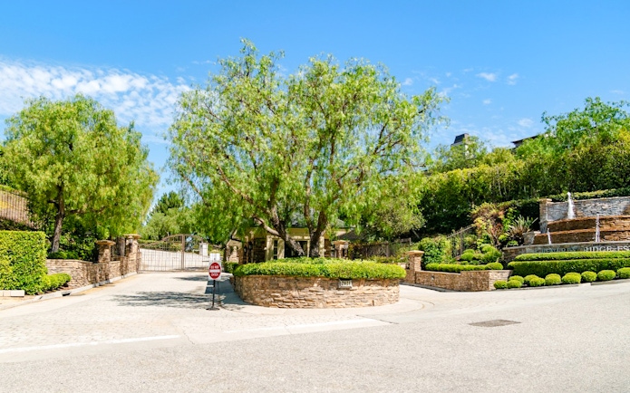 Gated entrance to a celebrity home in Los Angeles surrounded by lush greenery.