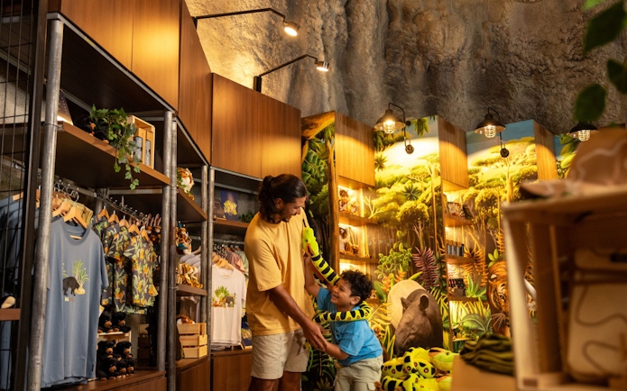 Father and child playing with plush snake in Rainforest Wild Adventure retail shop.