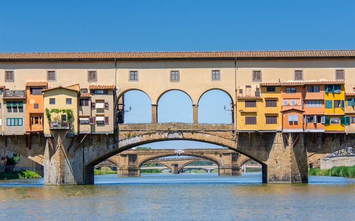 Florence tour bus crossing Ponte Vecchio bridge over the Arno River.