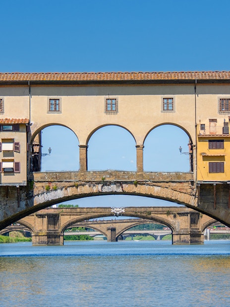 Florence tour bus crossing Ponte Vecchio bridge over the Arno River.