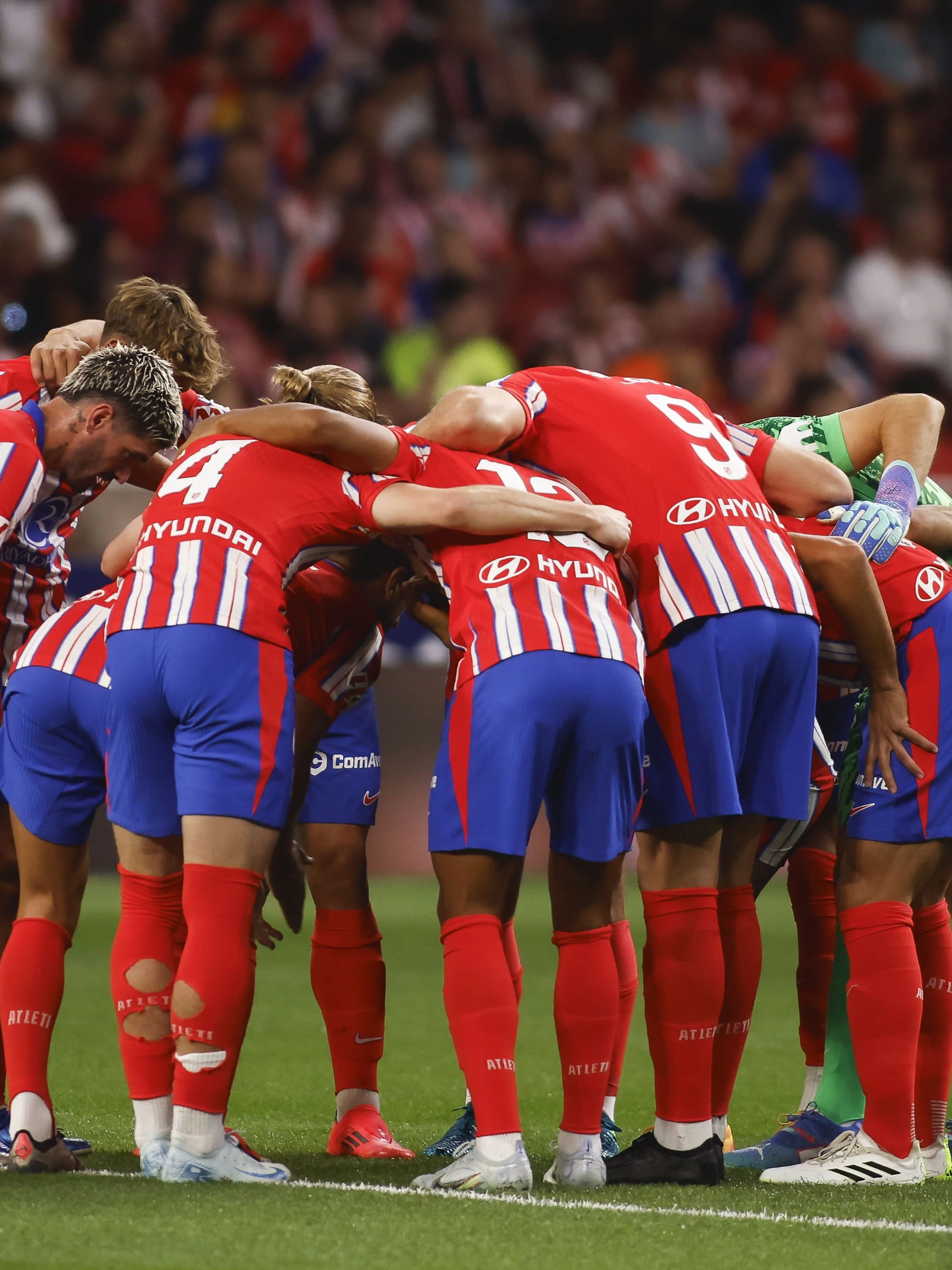 Atlético Madrid players in a team huddle during a match.