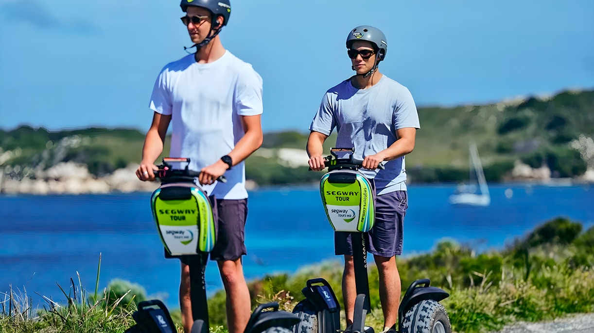 Tourist riding a Segway on Rottnest Island path with scenic coastal view in Perth, Australia.