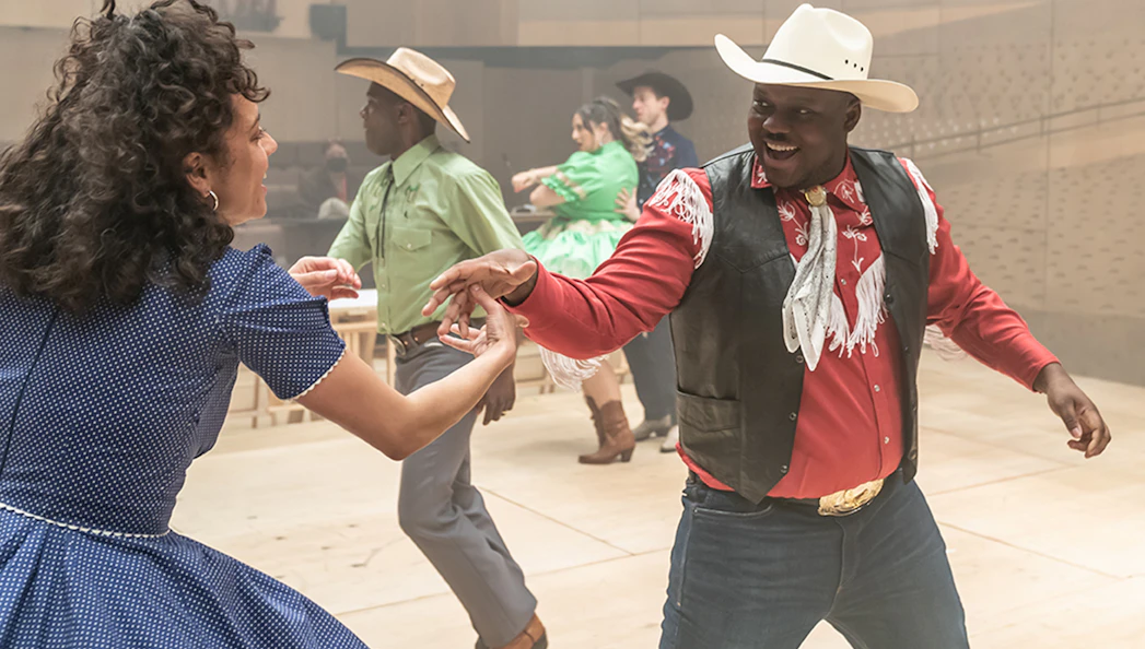 Dancers in cowboy attire performing a lively routine for the musical Oklahoma!