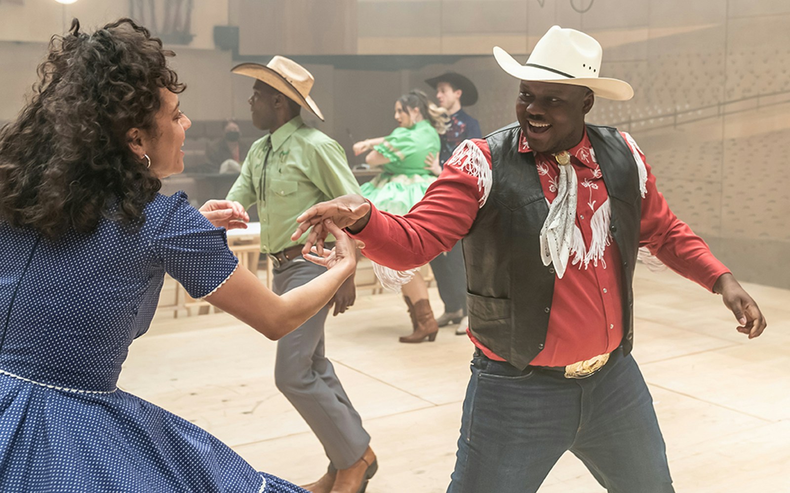Dancers in cowboy attire performing a lively routine for the musical Oklahoma!