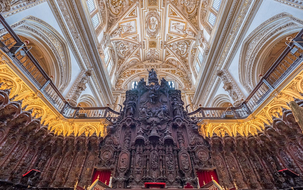 Ornate interior of the Mosque-Cathedral of Córdoba, featuring intricate wood carvings and detailed ceiling.