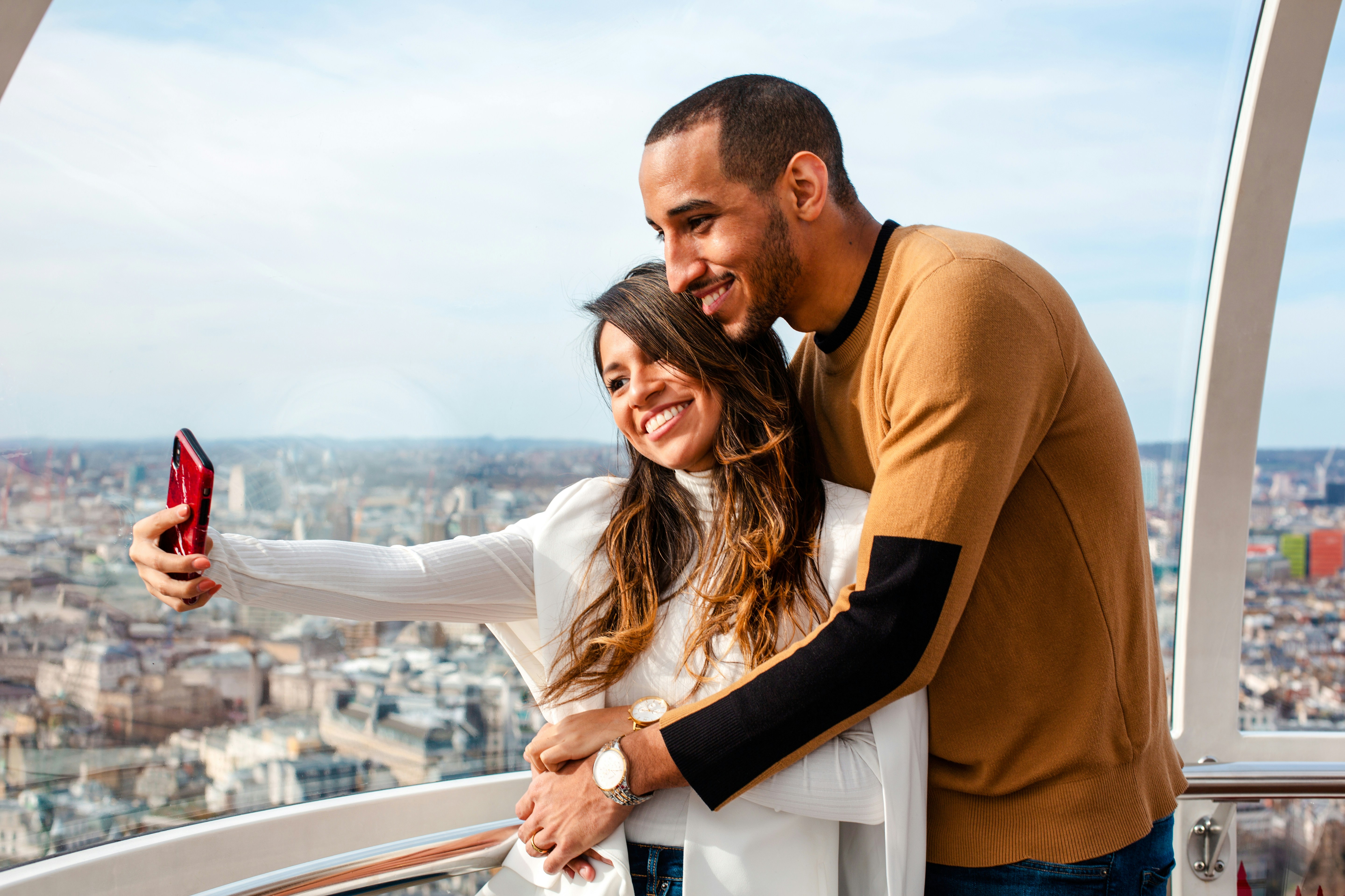 Couple taking a selfie on the London Eye with cityscape view.