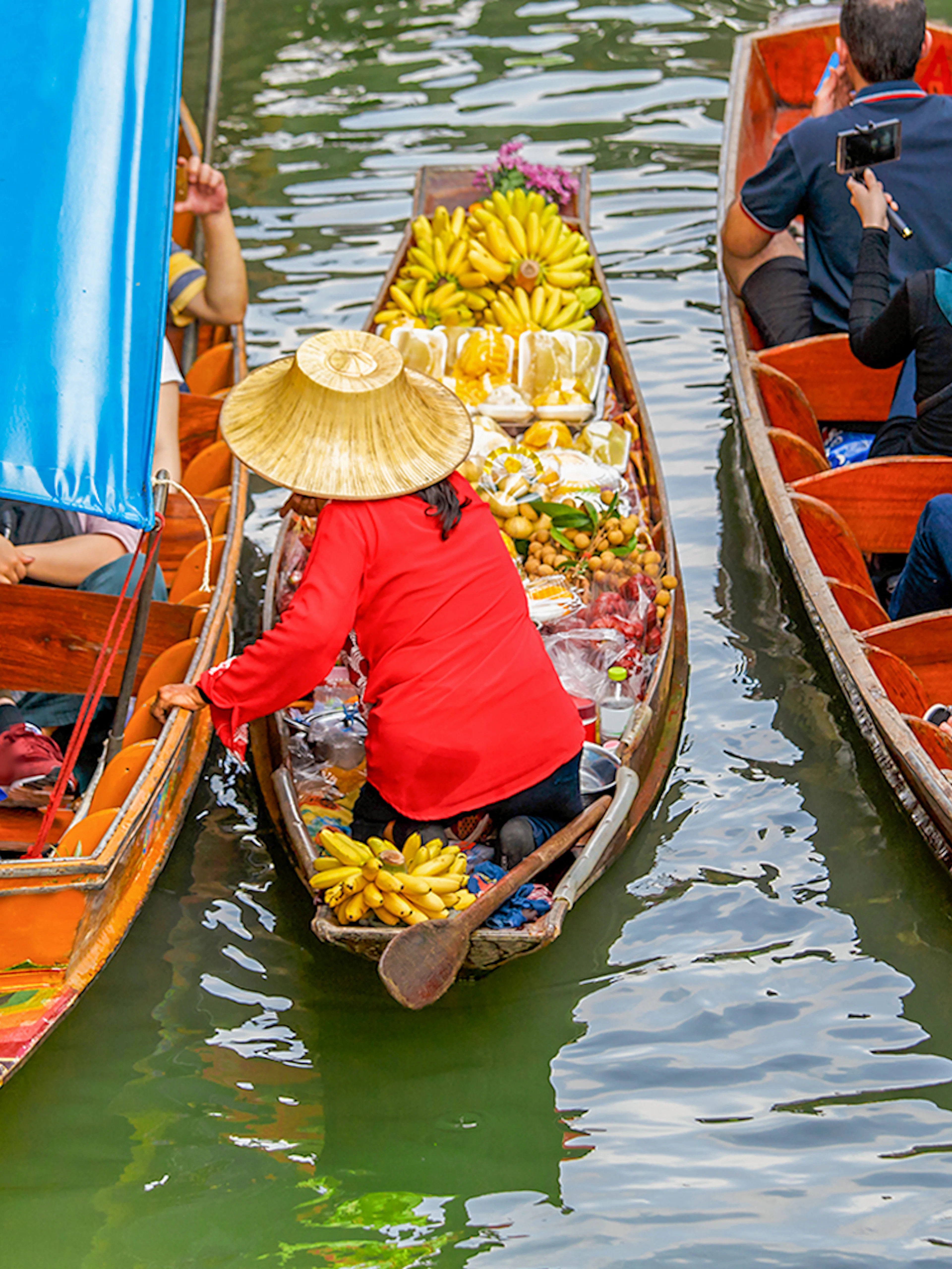 Fruit seller in a long tail boat at Damnoen Saduak Floating Market, Thailand.