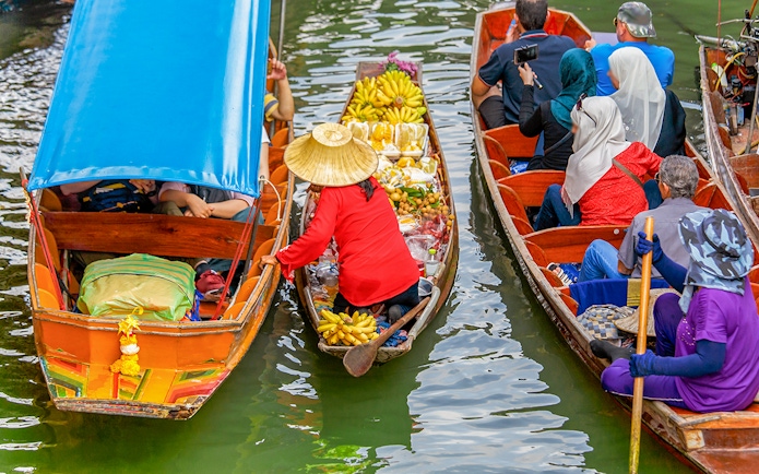 Fruit seller in a long tail boat at Damnoen Saduak Floating Market, Thailand.