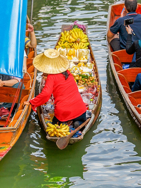 Fruit seller in a long tail boat at Damnoen Saduak Floating Market, Thailand.