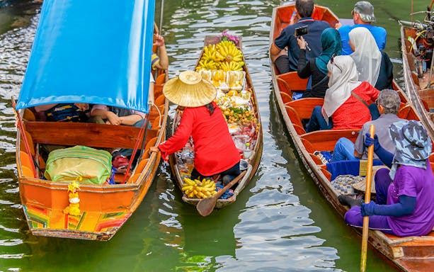 Fruit seller in a long tail boat at Damnoen Saduak Floating Market, Thailand.