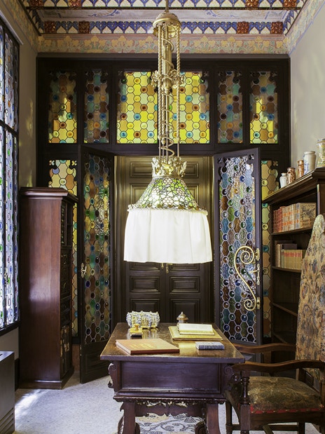 Stained glass interior of Casa Amatller with ornate wooden furniture and colorful windows.