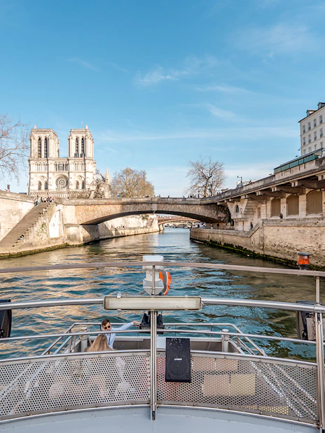 Seine River cruise view with Notre-Dame Cathedral and Parisian architecture.