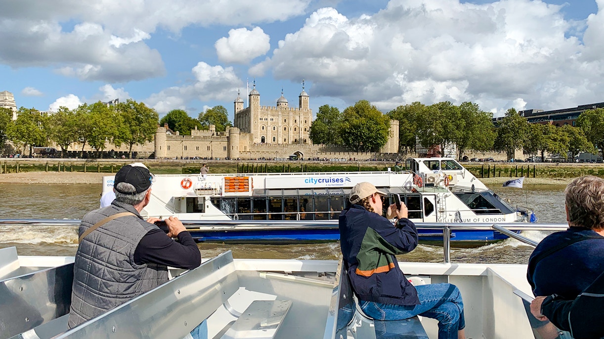 Sightseeing cruise passengers view the Tower of London from the Thames River.