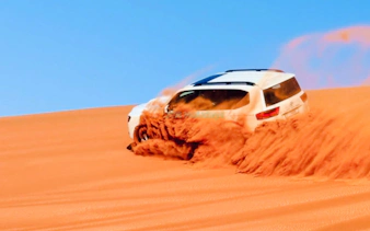 SUV driving through sand dunes during Abu Dhabi desert safari.