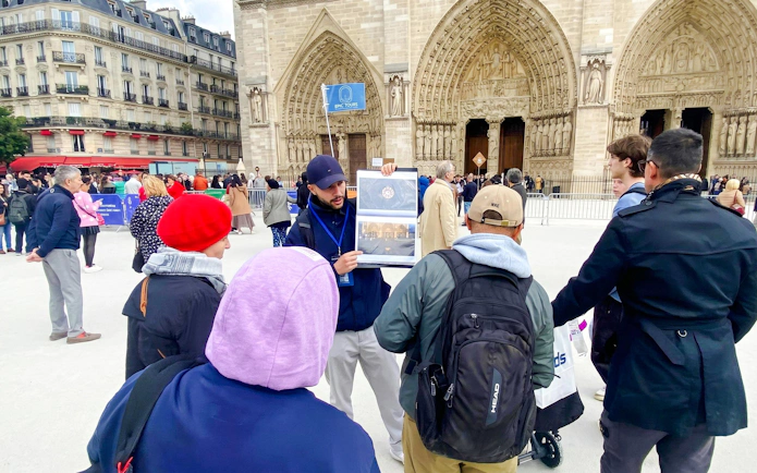 Tour guide explaining Notre-Dame's facade to a group in Paris.