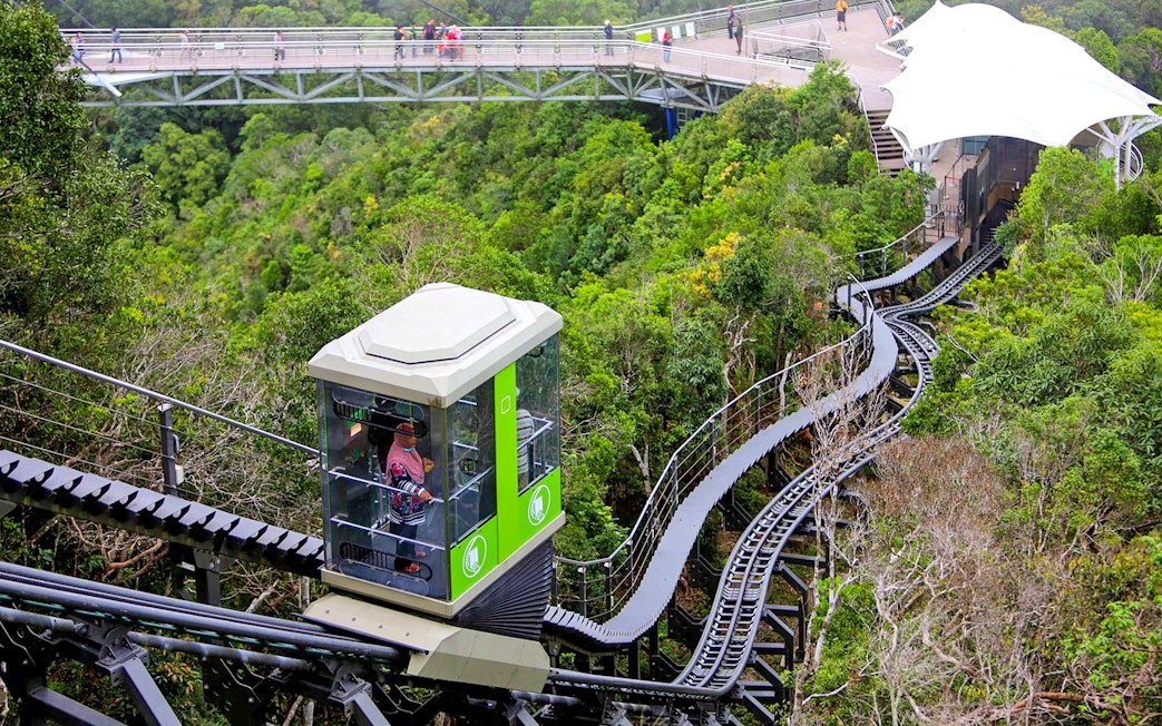 Langkawi Cable Car ascending through lush forest with a view of the sky bridge.