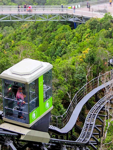 Langkawi Cable Car ascending through lush forest with a view of the sky bridge.