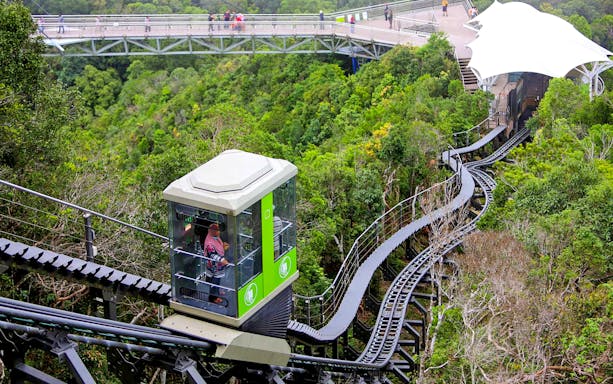 Langkawi Cable Car ascending through lush forest with a view of the sky bridge.
